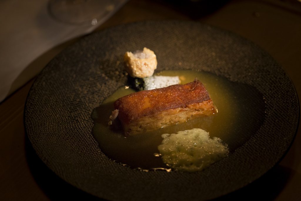 Cochinillo lacado, asado a baja temperatura con grelos, cortezas y jugo de almendras. / Sukalmedia.